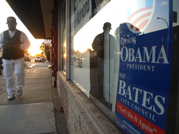 Man walking by Obama sign